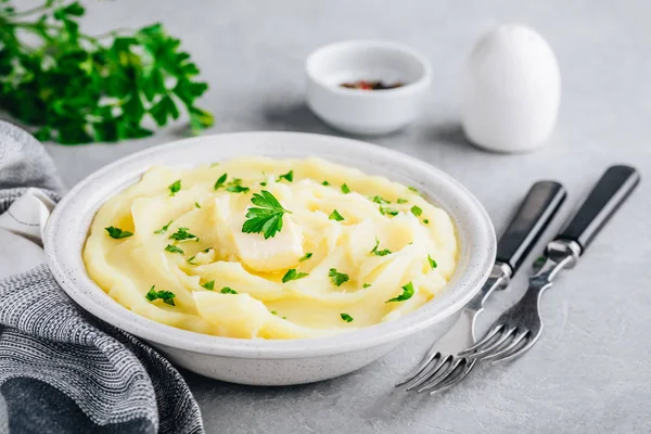 Картопляне пюре з маслом і свіжа петрушка в білій мисці на сірому кам'яному фоні . — стокове фото