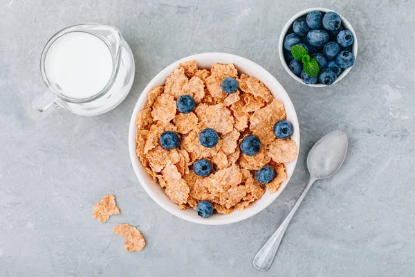 Whole grain breakfast cereal flakes with fresh blueberries and milk. Top view, copy space — Stock Photo, Image