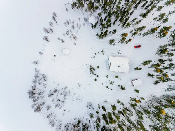 Vista aérea de la cabaña de madera en el bosque invernal de nieve junto al lago en la Finlandia rural —  Fotos de Stock