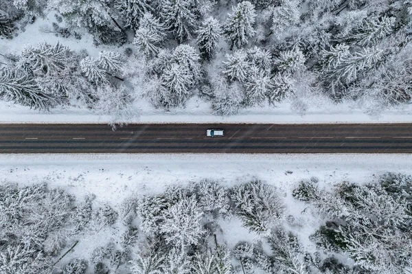 Vista aérea de la carretera de invierno con un coche y un bosque cubierto de nieve en Finlandia —  Fotos de Stock