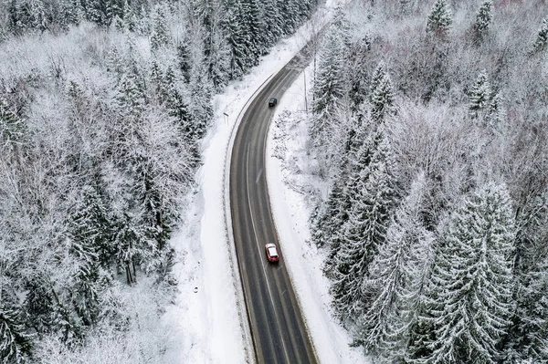 Vista aérea de la carretera de invierno con un coche y un bosque cubierto de nieve en Finlandia —  Fotos de Stock