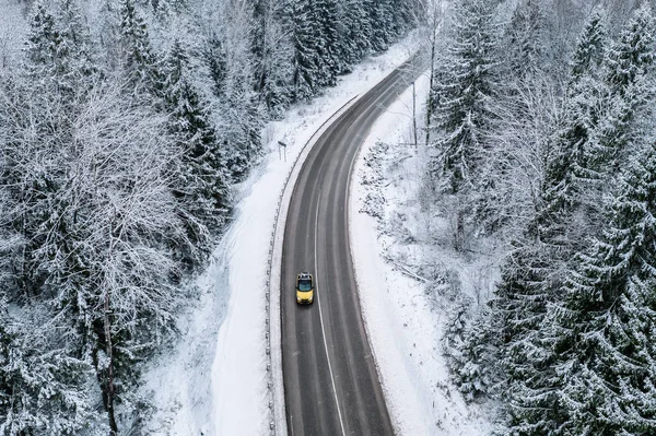 Letecký pohled na zimní silnici s autem a zasněženým lesem ve Finsku — Stock fotografie
