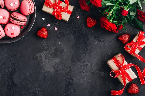 Fondo de San Valentín con macarrones rosados, rosas rojas, cajas de regalo y corazones rojos — Foto de Stock