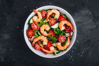 Taze yeşil marul ve turşu yapraklı karides salatası, salatalık, domates ve susam tohumları.. 