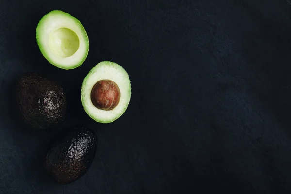 Avocado crudo su sfondo di pietra scura. Avocado fresco verde maturo per guacamole . — Foto Stock