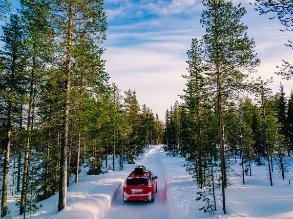 Rotes Auto mit Dachgepäckträger fährt im Winter auf schneebedeckter Waldstraße — Stockfoto