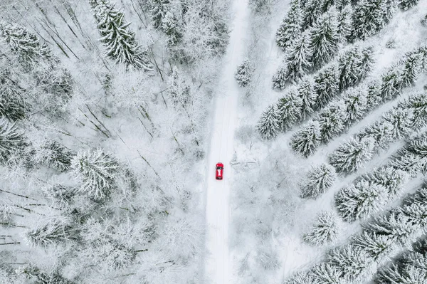 Légi kilátás hófödte erdő téli út és piros autó. — Stock Fotó