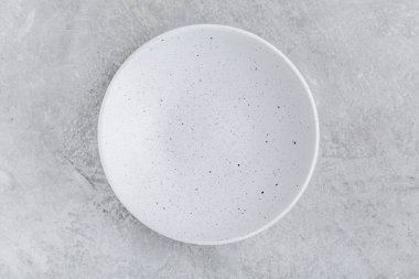 Empty white plate on gray concrete stone background.