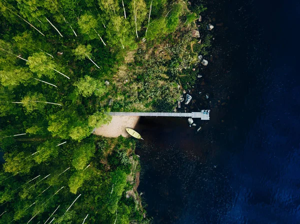 Vista aérea del muelle de madera con barco de pesca en el lago azul con bosque verde en Finlandia . — Foto de Stock
