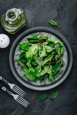 Salata için taze yeşil marul yapraklarını koyu taşlı arka planda karıştır, üst manzara, kopyalama alanı.