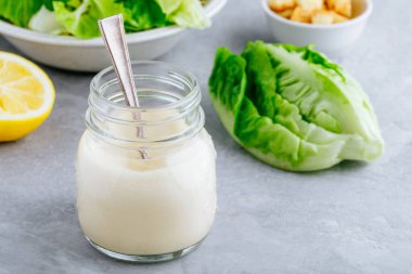 Ev yapımı Sezar Salatası gri taştan arka planda cam kavanoz gibi giyinmiş.