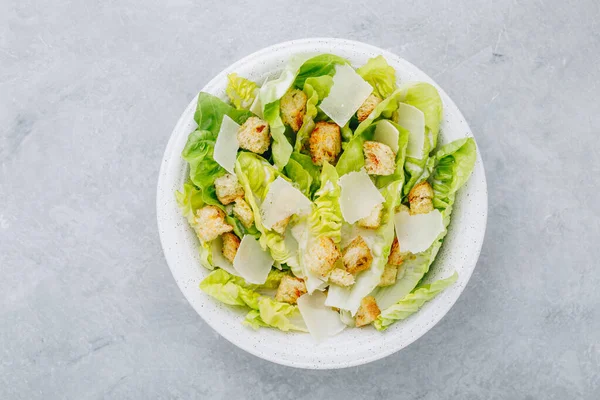 Classic Caesar Salad with Romaine Lettuce and creamy homemade dressing with Parmesan cheese and crunchy croutons. Top view, copy space.