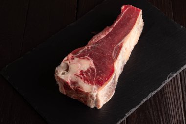 Taze çiğ sığır kaburgası kabaca siyah taştan bir tabakta doğranmıştır..