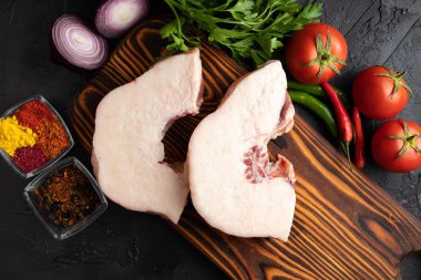 Ağaç kesme tahtasındaki kuzu parçaları baharatlar ve taze sebzelerle