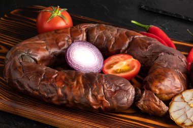 Tahta kesme tahtasının üzerinde tütsülenmiş at eti sosisi. Kazy, Kazakistan halkının geleneksel yemeği.