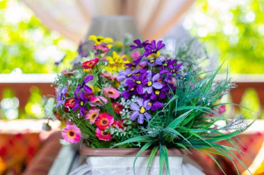 Bulanık arka planda parlak renkli suni çiçeklerle çiçeklenmiş.