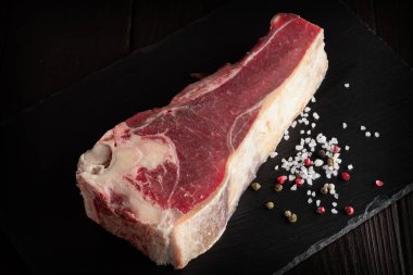 Taze çiğ sığır kaburgası kabaca siyah taştan bir tabakta doğranmıştır..
