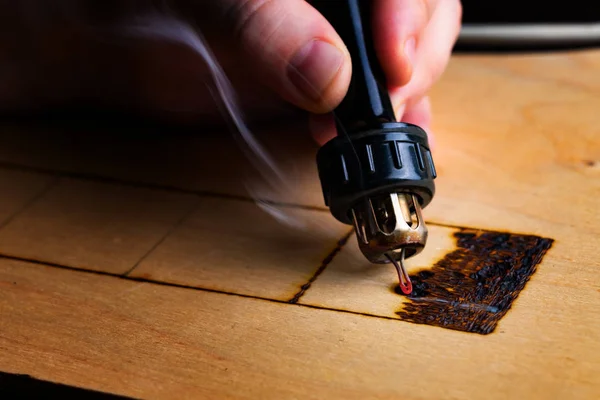 Pyrography. Pirografi kalemiyle odun yakılıyor. Kapat.