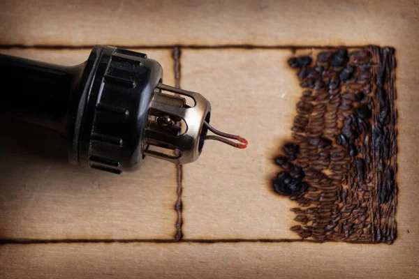 Pyrography. Pirografi kalemiyle odun yakılıyor. Kapat.