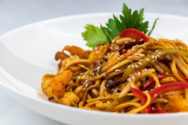 Pan asian food. Wok noodles on a white plate, close up