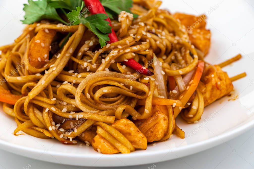Pan asian food. Wok noodles on a white plate, close up