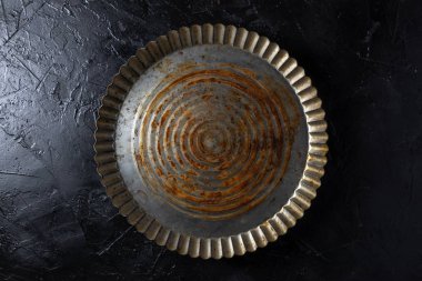 Koyu arkaplanda paslı, eski metal bir plaka.