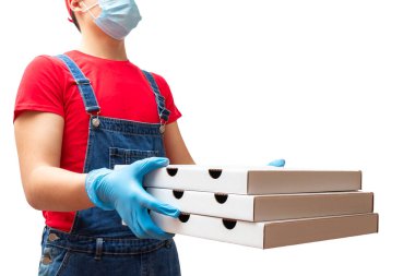Kırmızı tişörtlü, koruyucu maskeli ve eldivenli yemek siparişi veren ve beyaz arka planda izole edilmiş üç pizza kutusunu tutan adam.