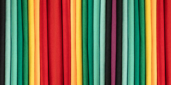 Background from colored cotton clothes. Colors of rainbow. Colored vertical strips of fabric. Banner