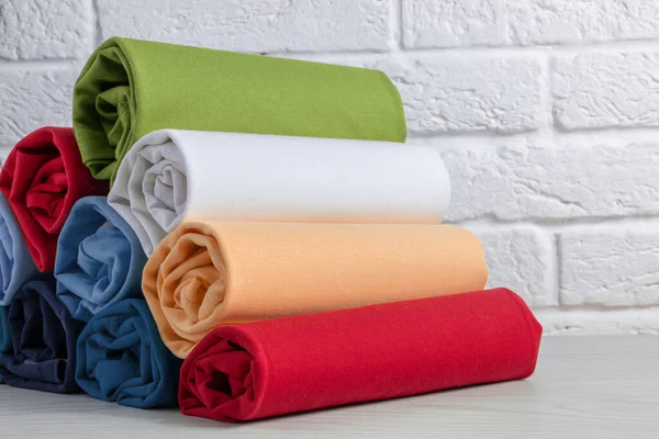 Açık ahşap bir masada renkli giysiler yığını. Yakın plan.