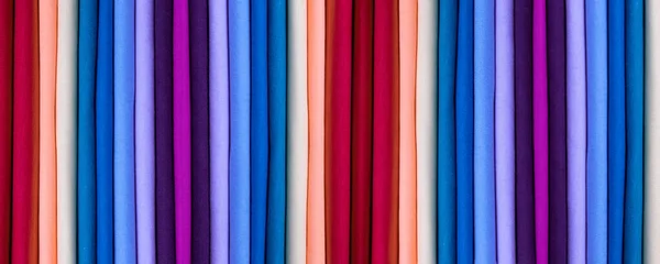 Background from colored cotton clothes. Colors of rainbow. Colored vertical strips of fabric. Banner