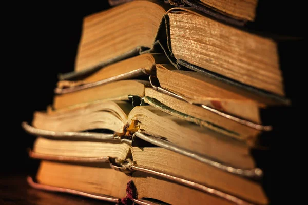 Karanlık bir arka planda çok eski bir kitap yığını. Eski tarz fotoğraf. Seçici odak