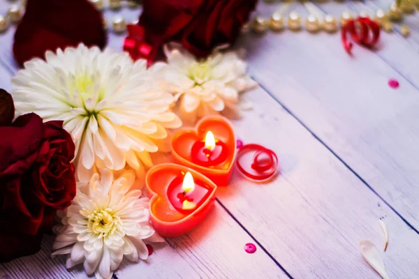 Due candele rosse ardenti cuori fiori arco vicino perle — Foto Stock