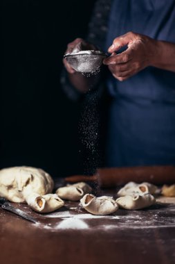Kadın geleneksel elma kurabiyelerinin üstüne pudra şekeri koyar..