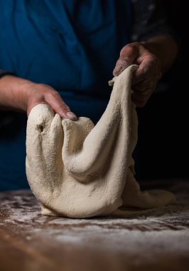 Büyükanne yemek pişiriyor, un hamuru hazırlıyor, büyükanne elleri kapalı. Üst düzey bir kadın kendi mutfağında hamur işi pişiriyor..