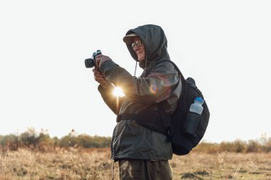 Yaşlı adam doğada fotoğraf çekiyor. Sonbahar ormanlarını fotoğraflayan adam..