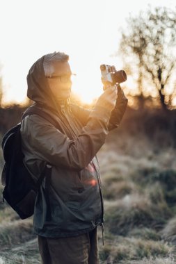 Yaşlı adam doğada fotoğraf çekiyor. Olgun bir adam sonbaharda ormanın fotoğraflarını çekiyor..