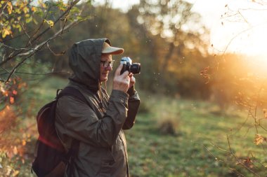 Kıdemli adam doğada fotoğraf çekiyor. Sonbahar ormanlarını fotoğraflayan adam..