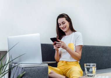 Kadın akıllı telefon kullanarak evde dinleniyor..