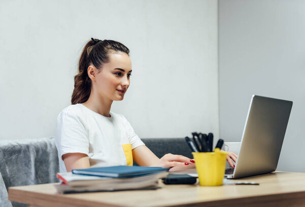 Asian  beauty sitting on couch & working on laptop from home.