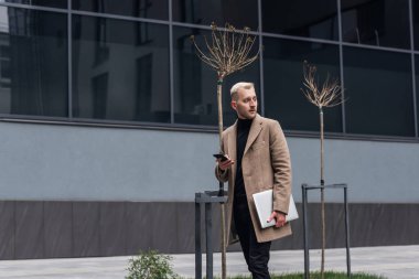 Şehir caddesinde dizüstü bilgisayarla yürüyen işadamı.