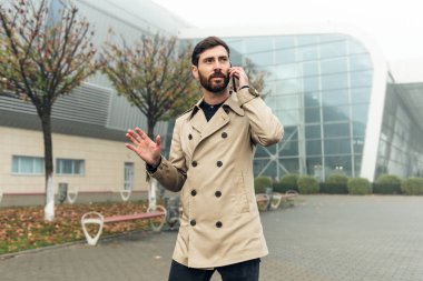 Başarılı bir iş adamı aceleyle merdivenlerde koşuyor ve saatlerine bakıyor. Ofis müdürü gecikti. Endüstriyel binaların yanında yürüyüp telefonla konuşuyor. Zaman yönetimi. Ofis. İş dünyası.