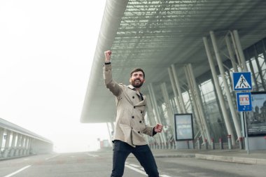 Neşeli ve mutlu iş adamı aktif olarak bir havaalanında dans ediyor..