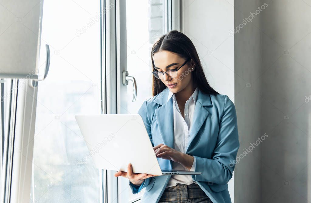 Young beautiful businesswoman in glasses working on laptop