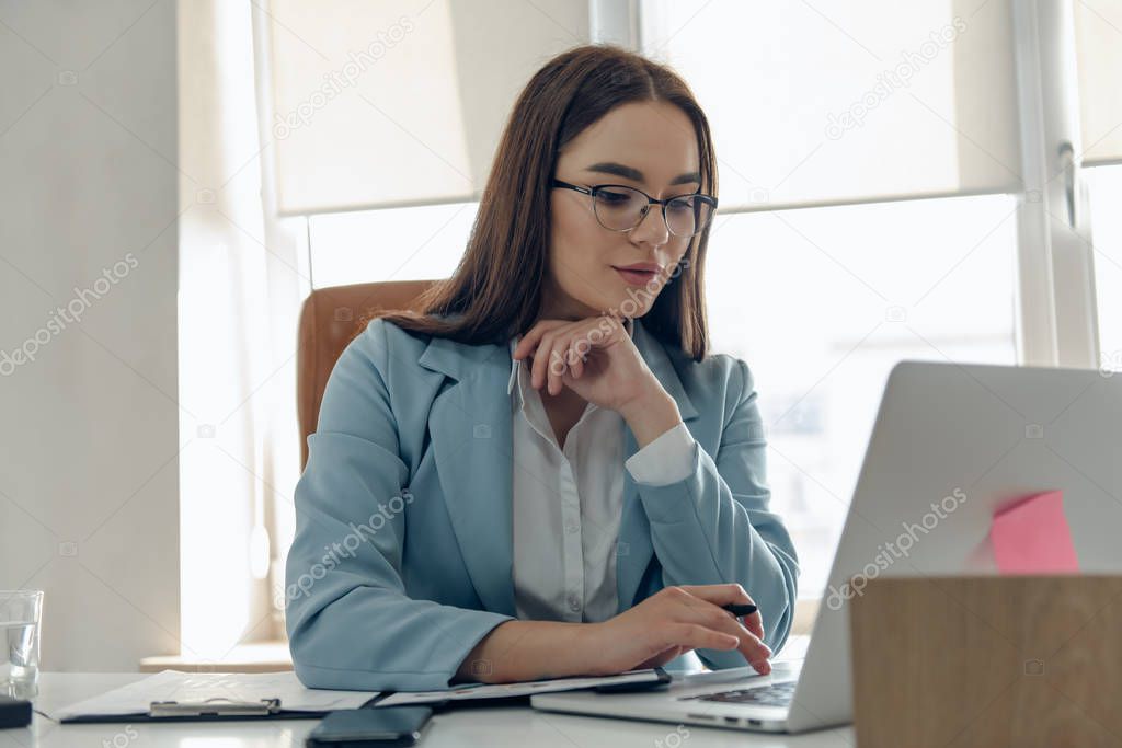 Young business woman working on laptop in office.