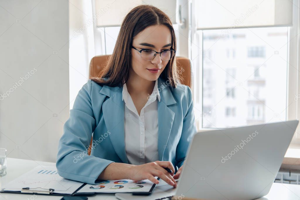 Young business woman working on laptop in office.