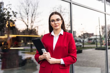 Güzel genç iş kadını gülümsüyor ve elinde belgeler tutuyor..