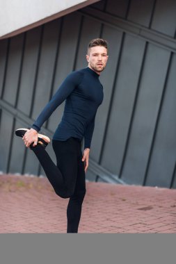 Fitness adamı bacak kaslarını gevşetiyor. Spor, egzersiz, sağlıklı yaşam tarzı konsepti.