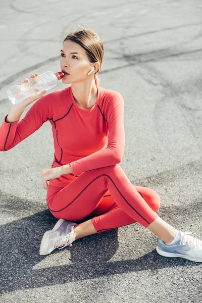 Fit young lady drinking water after workout.