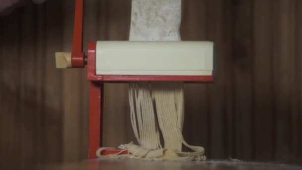Pasta de espagueti fresca saliendo del primer plano de la máquina de pasta. Las manos de las mujeres usan una máquina cortadora de pasta. Movimiento lento . — Vídeo de stock