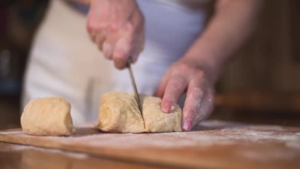 Close up hands cut shape in rolling-pin dough into pieces on wooden board covered with flour — Stock Video